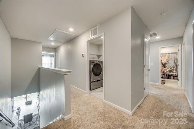 hallway with attic access, light colored carpet, visible vents, and an upstairs landing