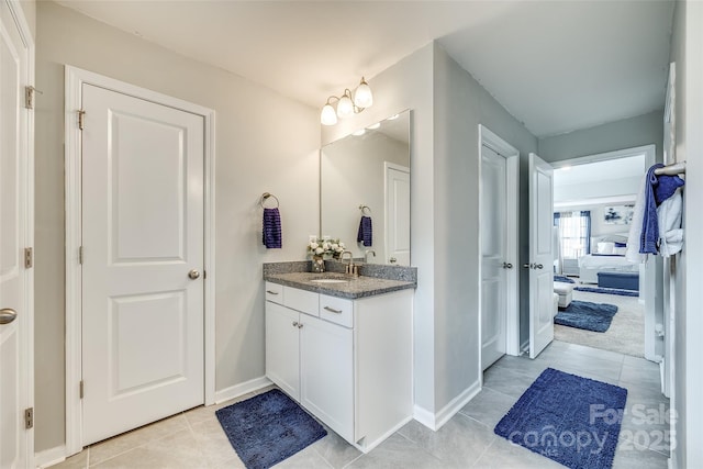 bathroom with tile patterned flooring, connected bathroom, vanity, and baseboards