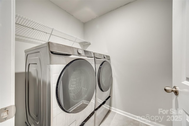 clothes washing area featuring laundry area, light tile patterned floors, baseboards, and separate washer and dryer