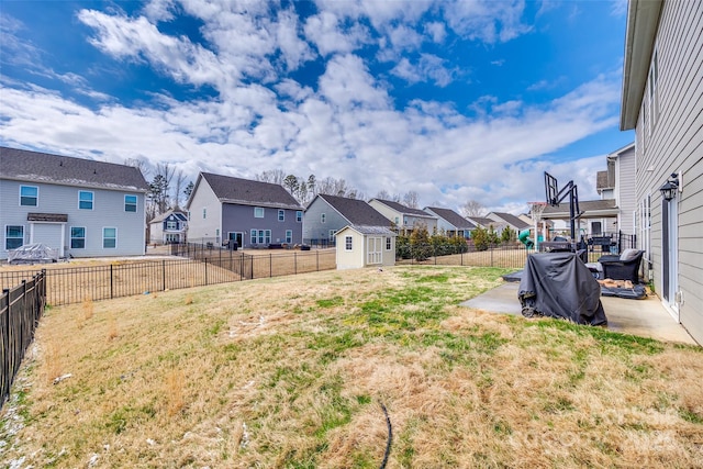 view of yard featuring a residential view, a fenced backyard, an outbuilding, and a storage unit