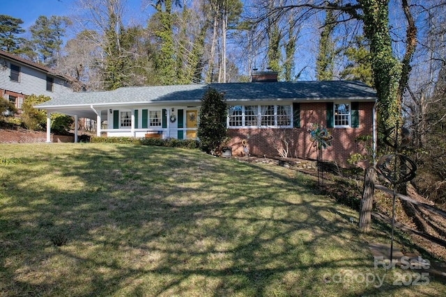 view of front of home with a carport, brick siding, a chimney, and a front lawn