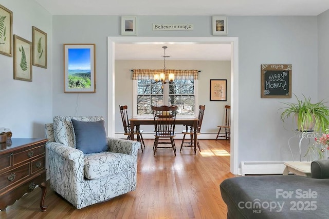 dining space with a baseboard heating unit, a notable chandelier, baseboards, and wood finished floors