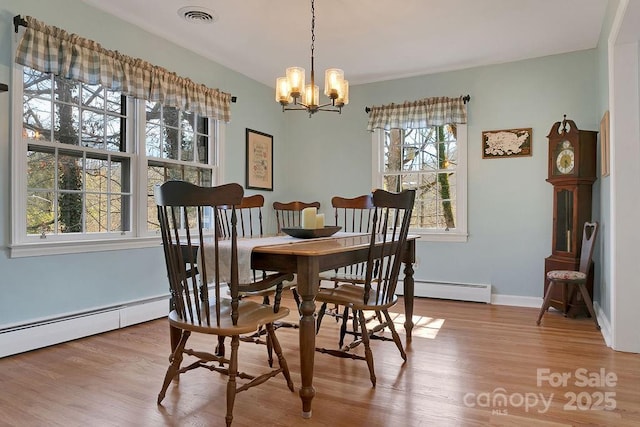 dining space with light wood-type flooring, baseboards, visible vents, and a chandelier