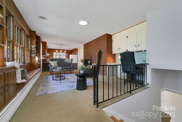 living room with light carpet, a baseboard radiator, a chandelier, and visible vents