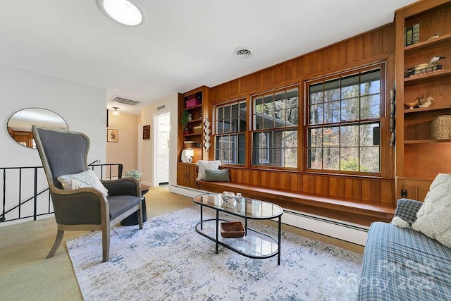 sitting room with light colored carpet, visible vents, and wooden walls