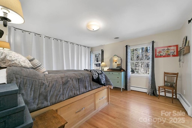 bedroom with light wood-style flooring and a baseboard heating unit