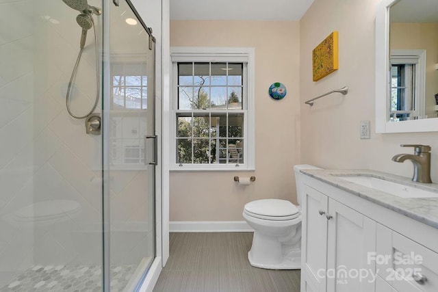 full bathroom featuring vanity, a shower stall, toilet, and baseboards