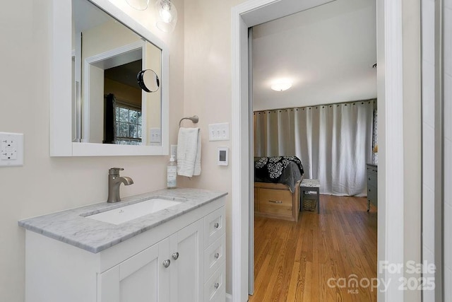 ensuite bathroom with ensuite bath, wood finished floors, and vanity