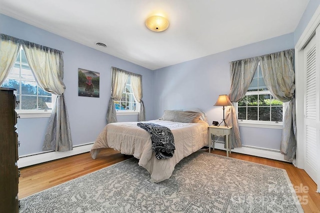 bedroom featuring baseboard heating and wood finished floors