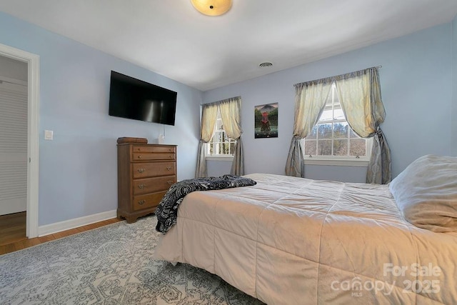 bedroom with wood finished floors, visible vents, and baseboards