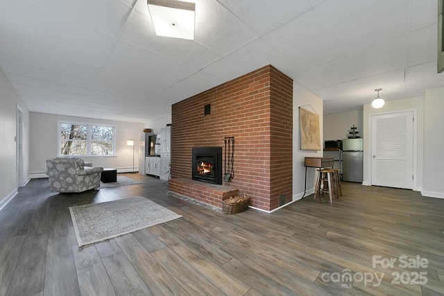 unfurnished living room featuring dark wood-style floors, baseboards, a fireplace, and baseboard heating