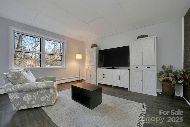 living room with a baseboard heating unit, dark wood-type flooring, baseboard heating, and baseboards