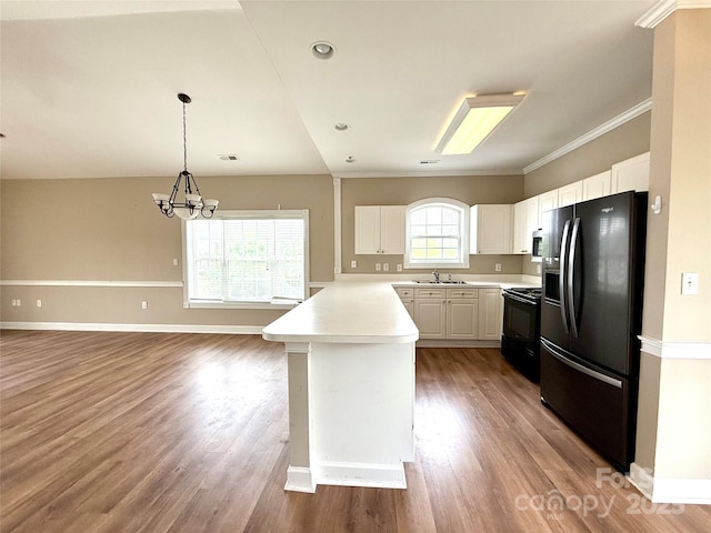 kitchen with a sink, black appliances, a chandelier, light countertops, and a peninsula