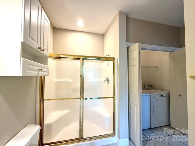 full bathroom with a shower stall, tile patterned floors, baseboards, washing machine and dryer, and toilet