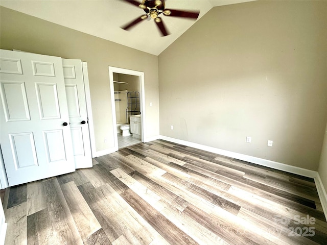 unfurnished bedroom with wood finished floors, baseboards, vaulted ceiling, and ensuite bath