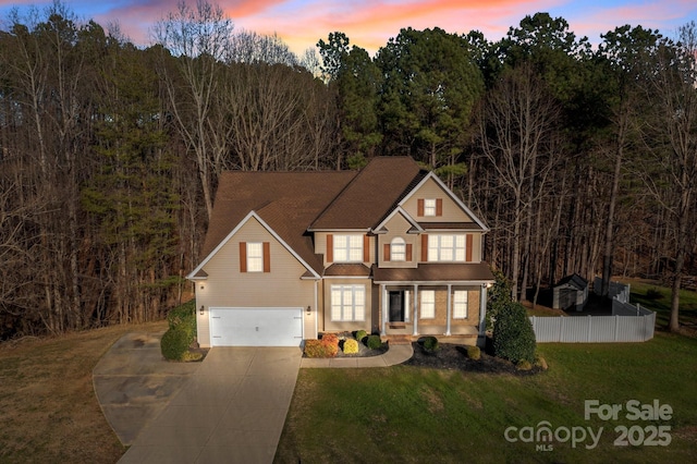 traditional-style house featuring covered porch, a garage, fence, driveway, and a front lawn