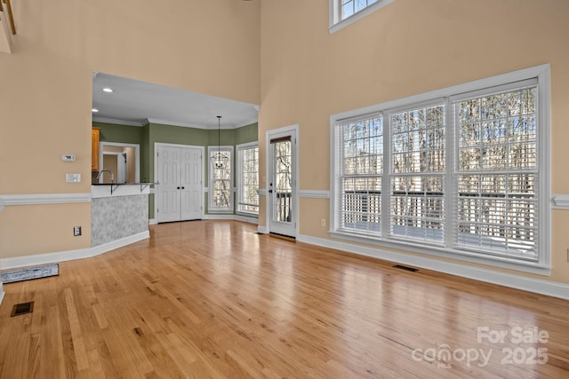 unfurnished living room featuring a wealth of natural light, visible vents, and light wood-style flooring