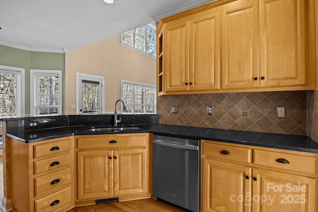 kitchen featuring a peninsula, a sink, dishwasher, dark stone countertops, and crown molding