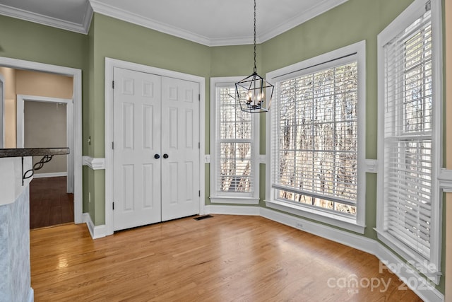 unfurnished dining area featuring plenty of natural light, light wood-type flooring, and crown molding