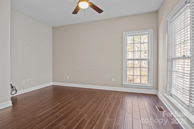 unfurnished room with visible vents, dark wood finished floors, baseboards, and ceiling fan