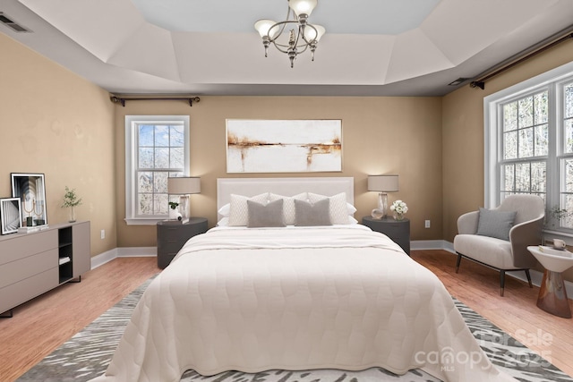 bedroom featuring visible vents, a raised ceiling, and wood finished floors