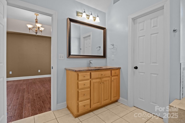 bathroom with tile patterned flooring, baseboards, a notable chandelier, and vanity