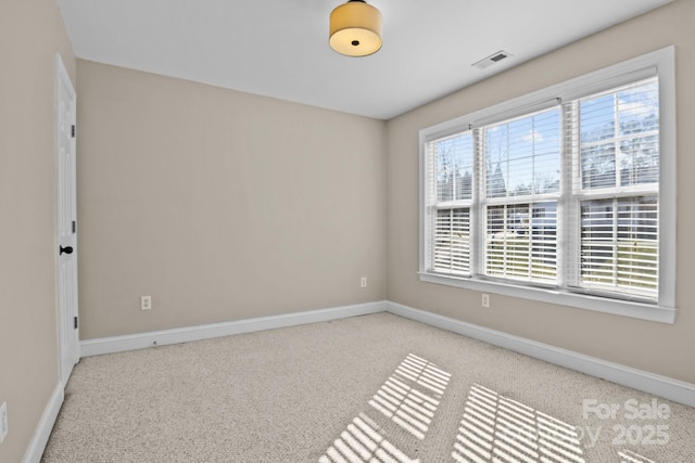 spare room featuring visible vents, baseboards, and light colored carpet