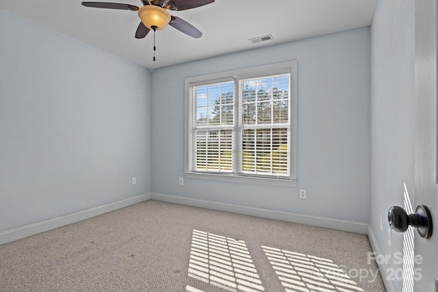 empty room with ceiling fan, light colored carpet, visible vents, and baseboards