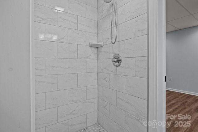 bathroom with tiled shower and wood finished floors