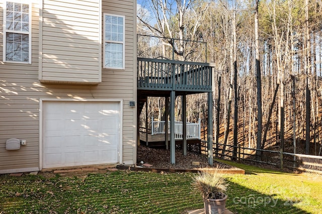 back of property featuring a yard, an attached garage, fence, and a wooden deck