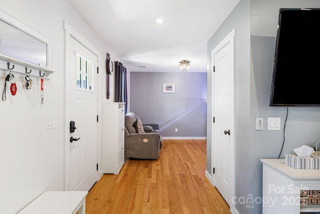 hall with light wood-style floors and baseboards