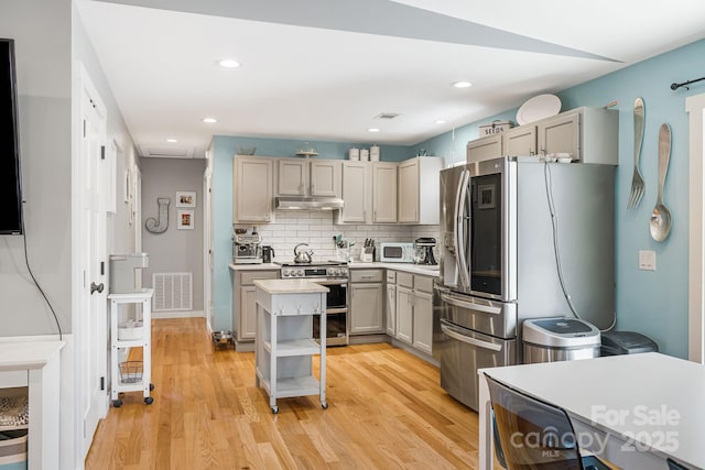 kitchen with light countertops, appliances with stainless steel finishes, visible vents, and under cabinet range hood