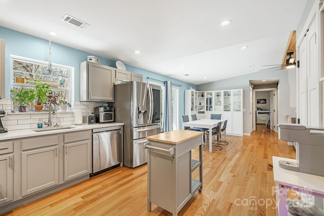 kitchen with visible vents, stainless steel appliances, light countertops, gray cabinetry, and a sink