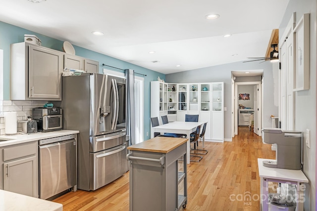 kitchen featuring backsplash, light wood-style flooring, appliances with stainless steel finishes, a kitchen island, and butcher block countertops