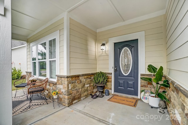 view of exterior entry featuring stone siding and a porch