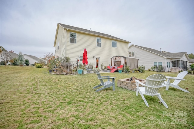 rear view of property featuring a yard and a fire pit