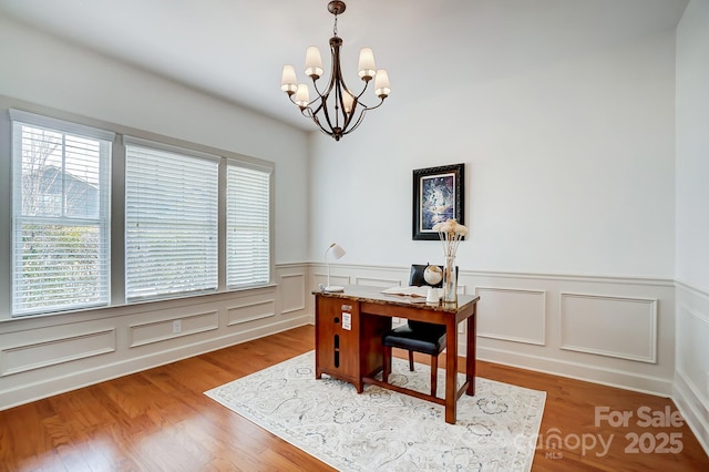 office space with a notable chandelier, a decorative wall, and wood finished floors