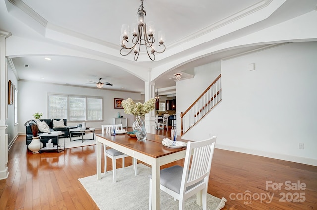 dining room with light wood finished floors, stairway, arched walkways, and crown molding