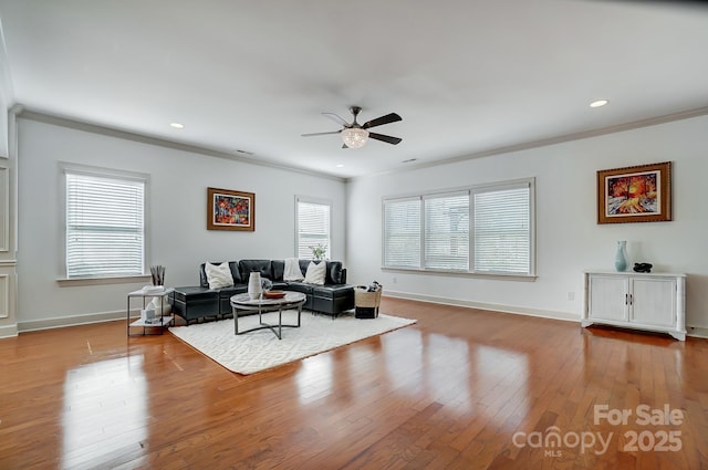 living area featuring recessed lighting, hardwood / wood-style floors, ornamental molding, ceiling fan, and baseboards