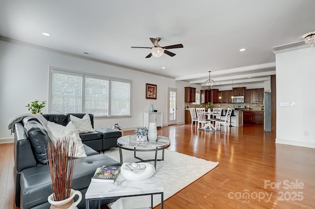 living room with light wood-style floors, ornamental molding, and a ceiling fan