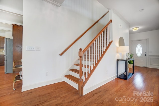 entryway featuring baseboards, stairs, ornamental molding, and wood finished floors