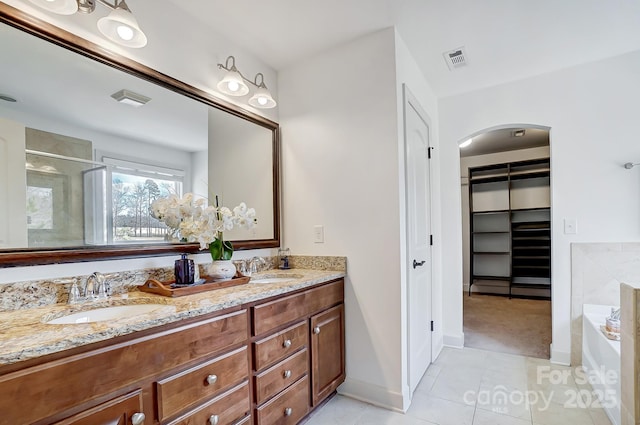 full bathroom with a bath, double vanity, visible vents, and a sink