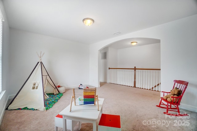 recreation room featuring arched walkways, carpet flooring, and baseboards