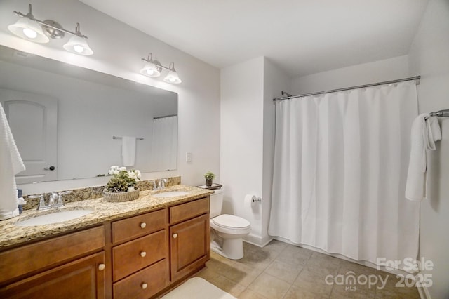 bathroom with tile patterned flooring, a sink, toilet, and double vanity