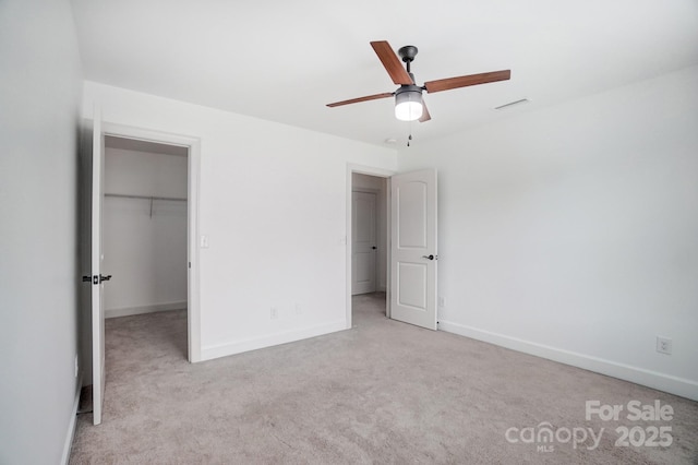 unfurnished bedroom with carpet floors, visible vents, a spacious closet, a ceiling fan, and baseboards