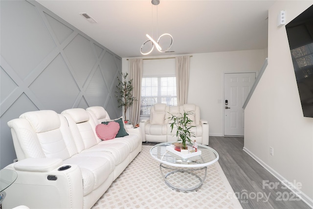 living room with baseboards, visible vents, an inviting chandelier, and wood finished floors