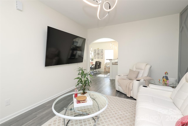 living room featuring arched walkways, dark wood-style flooring, and baseboards