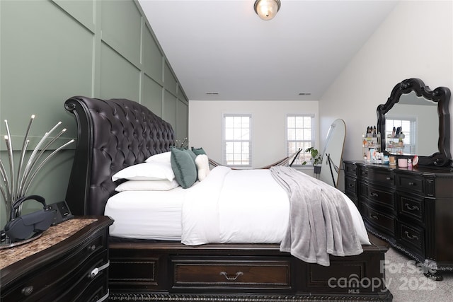 bedroom with light carpet, visible vents, and vaulted ceiling