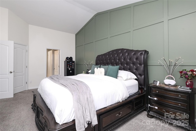 bedroom with lofted ceiling, light carpet, and a decorative wall