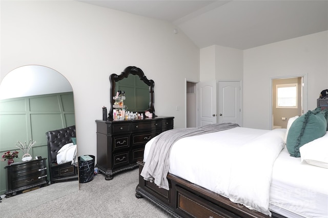 bedroom featuring lofted ceiling, ensuite bath, and light colored carpet